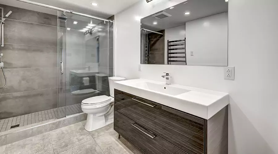 Modern bathroom remodel with dark blue subway tile, light wood vanity, and black fixtures